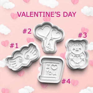 May include: Four white plastic cookie cutters shaped like a heart with wings, a pair of balloons, a teddy bear holding a heart, and a scroll with the text "I love you".