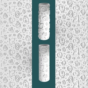 May include: White paint roller with a repeating pattern of sea creatures, including fish, stingrays, and starfish. The roller is cylindrical and features a textured surface. The design is embossed, creating a 3D effect. The background shows the same pattern.