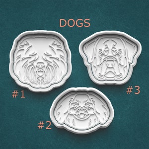 May include: Three white cookie cutters shaped like dog faces. The cookie cutters are labeled #1, #2, and #3. The text "DOGS" is at the top of the image.