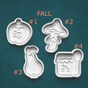 May include: Four white plastic cookie cutters in the shapes of an apple, mushroom, pear, and a jar of jam with a spoon. The word "FALL" is written in orange above the cutters. Numbers 1-4 are next to each cutter.