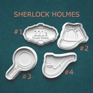 May include: Four white cookie cutters with a Sherlock Holmes theme. Includes a sign that reads "221B Baker Street", a deerstalker hat, a magnifying glass, and a smoking pipe. The text "SHERLOCK HOLMES" is at the top.