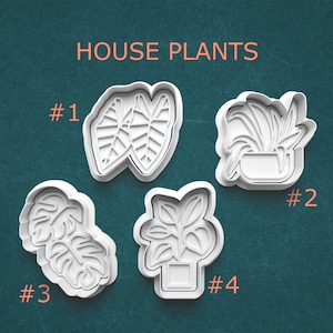 May include: Four white plastic cookie cutters in the shape of house plants. The cutters are labeled #1, #2, #3, and #4. The text "HOUSE PLANTS" is in orange at the top of the image.