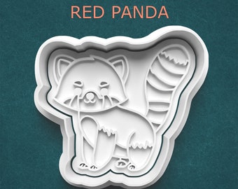 May include: A white plastic cookie cutter shaped like a red panda with a striped tail and facial features. The text RED PANDA is printed in light orange above the cutter. The design features a detailed outline of the animal's body.