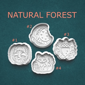 May include: Four white plastic cookie cutters with nature-themed designs. The cutters include a mushroom cluster, a crescent moon with leaves, an acorn, and a fox with mushrooms. The words "NATURAL FOREST" are printed above the cutters.
