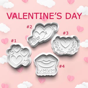 May include: Four white plastic cookie cutters in Valentine's Day shapes: hearts, lips with XOXO, and a heart pierced by an arrow. The words "VALENTINE'S DAY" are in pink text above the cutters. Pink hearts and white clouds decorate the background.