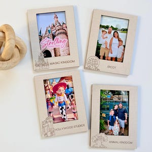 May include: Four beige photo frames with images from Disney parks. Each frame has a different park name etched at the bottom: Magic Kingdom, Epcot, Hollywood Studios, and Animal Kingdom. A wooden decorative knot is in the upper left.