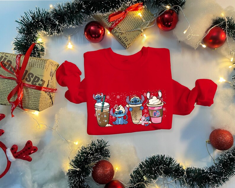 May include: Red Christmas sweater with a graphic of four Stitch characters holding different holiday drinks. The characters are wearing Santa hats and holding cups of coffee, hot chocolate, and eggnog.