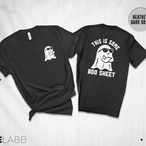 以下が含まれることがあります： ヘザーダークグレーのTシャツ。背面にはサングラスをかけた白い幽霊と「This is some boo sheet」の文字がプリントされています。前面には、サングラスをかけた小さな白い幽霊がプリントされています。