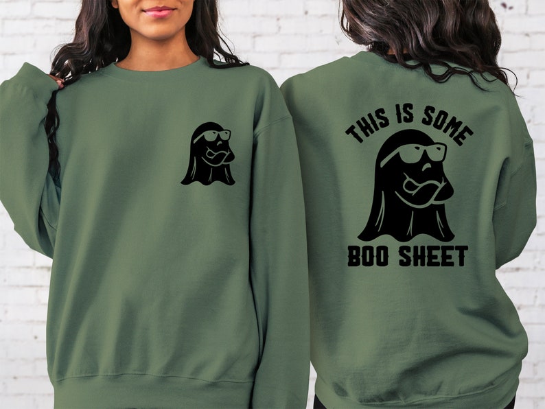 以下が含まれることがあります： 黒いサングラスをかけた黒い幽霊と「This is some boo sheet」という文字が背中に書かれた緑色のスウェットシャツ。スウェットシャツの前には、黒いサングラスをかけた小さな黒い幽霊が描かれている。