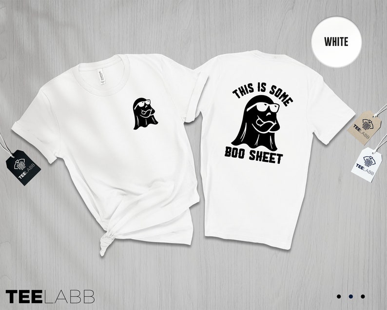 以下が含まれることがあります： 白いTシャツに、サングラスをかけた幽霊が描かれており、後ろには「This is some boo sheet」という文字が書かれています。Tシャツの前には、小さな幽霊のグラフィックが描かれています。
