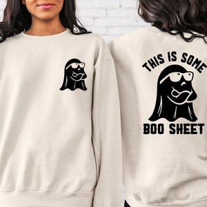 以下が含まれることがあります： 前面にサングラスをかけた黒い幽霊、後ろに「This is some boo sheet」という文字とサングラスをかけた黒い幽霊が描かれた白いスウェットシャツです。