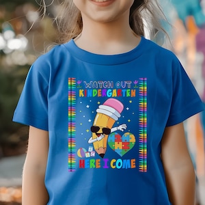 May include: A blue t-shirt with a colorful graphic of a pencil wearing sunglasses and a graduation cap. The text on the shirt reads "Watch Out Kindergarten Here I Come".