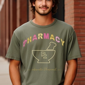 Peut inclure: Un t-shirt vert avec le mot "Pharmacy" en lettres roses et dorées, un mortier et un pilon avec un symbole Rx et le texte "Informative Pharmacist" en cursive.
