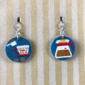 Könnte beinhalten: Ein Paar blaue und weiße Stoffohrringe mit einem Kaffeekanne- und Kaffeetassen-Design.