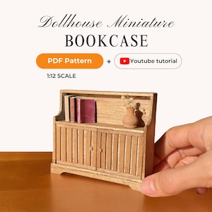 May include: A miniature wooden bookcase with two doors and a top shelf, holding three books and a small vase. The text "Dollhouse Miniature BOOKCASE" is at the top, with "PDF Pattern" and "YouTube tutorial" icons. The scale is 1:12.