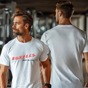 May include: White crew neck t-shirt with the text "B.U.R.P.E.E.S. Don't Do Them" in red. The shirt is worn by a person in a gym setting. The person is wearing a black watch.