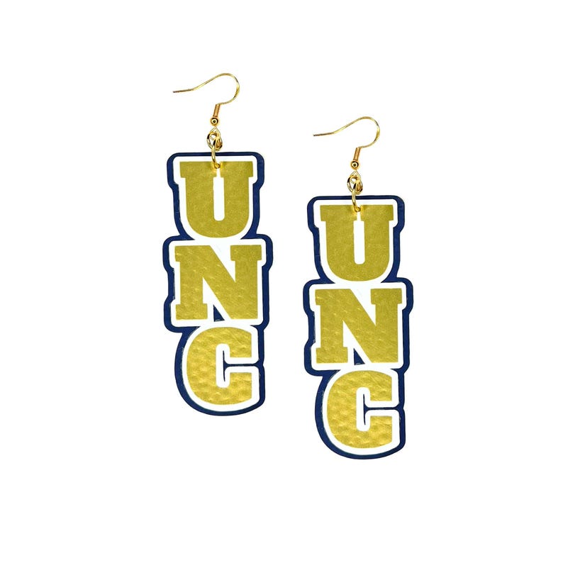 K&ouml;nnte beinhalten: Goldene UNC-Ohrringe mit blauem Umriss. Die Buchstaben sind vertikal &uuml;bereinander angeordnet und haben eine strukturierte Oberfl&auml;che.