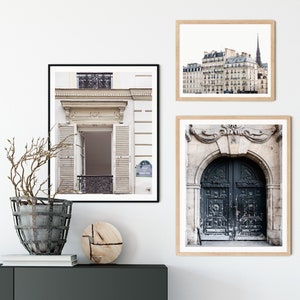 May include: Three framed prints of Parisian architecture. The top print shows a building with a tall spire. The middle print shows a white building with a doorway and shutters. The bottom print shows a black door with ornate details.