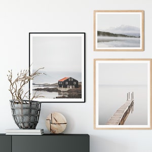 May include: Three framed photographs of foggy landscapes with water. The top photo shows a lake with a mountain in the background. The middle photo shows a black house on a lake with a rocky shore. The bottom photo shows a wooden dock extending into a lake.
