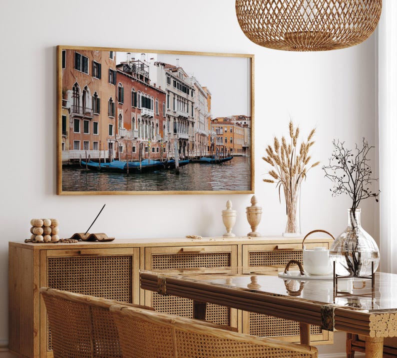 May include: A framed photograph of a canal in Venice, Italy. The photo shows a row of colorful buildings along the canal with gondolas floating in the water.