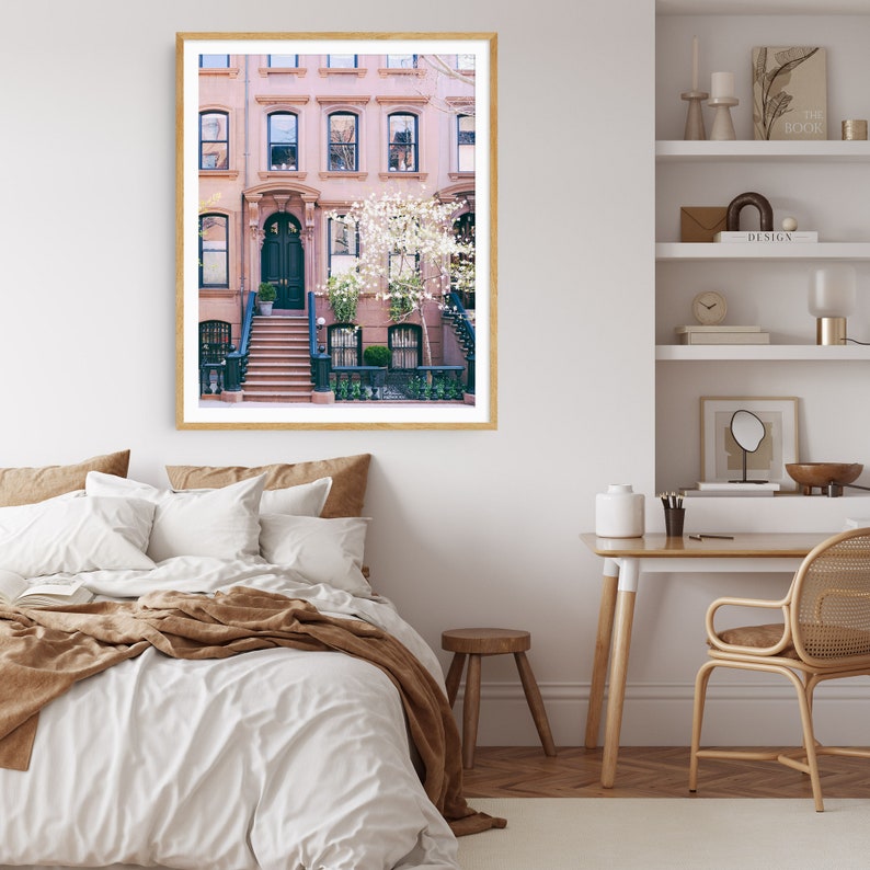 May include: A photograph of a row of brown brick townhouses with a green door and white flowers in front. The houses have white window frames and are in a city setting.