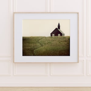 K&ouml;nnte beinhalten: Eine schwarze Holzkirche mit einem Kirchturm steht auf einem grasbewachsenen H&uuml;gel. Die Kirche hat zwei Fenster und eine T&uuml;r. Das Gras ist gr&uuml;n und braun.