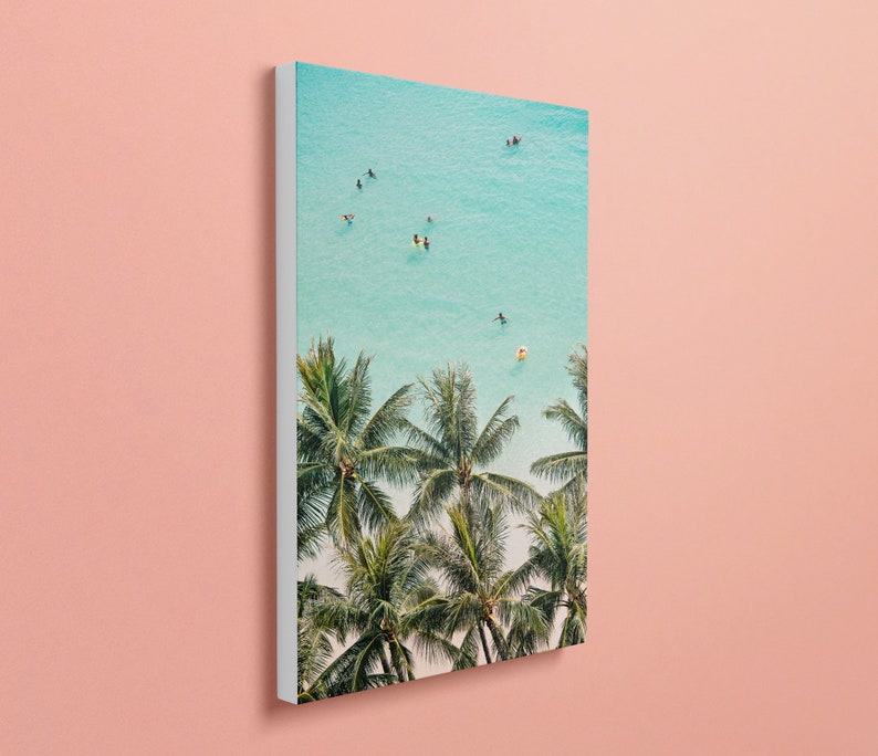 May include: An aerial view of a tropical beach with turquoise water and palm trees. People are swimming and floating in the water.