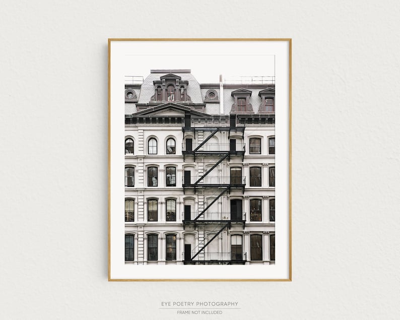 Puede incluir: Una fotograf&iacute;a en blanco y negro de un edificio alto y estrecho con una escalera de incendios. El edificio tiene muchas ventanas y est&aacute; pintado de blanco. La escalera de incendios est&aacute; hecha de metal y est&aacute; pintada de negro.