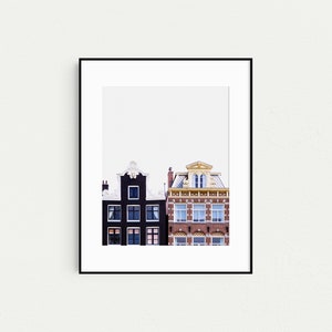 May include: A black and white photograph of two buildings in Amsterdam, Netherlands. The building on the left is black with white trim and the building on the right is red brick with a yellow trim.