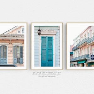 May include: Three framed photographs of colorful buildings in New Orleans, Louisiana. The first photo shows a pink building with blue doors and windows. The second photo shows a blue building with a teal door and shutters. The third photo shows a row of pink buildings with black balconies and a sign that reads "Royal Antiques".
