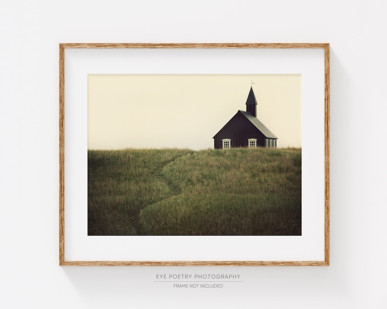 K&ouml;nnte beinhalten: Eine schwarze Holzkirche mit einem Kirchturm steht auf einem grasbewachsenen H&uuml;gel. Die Kirche hat zwei Fenster und eine T&uuml;r. Der Himmel ist hellgelb.