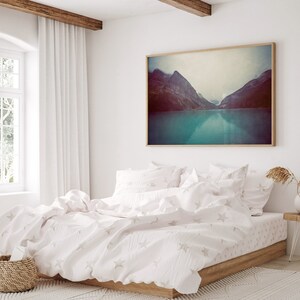May include: A white bed with a white duvet cover and white pillowcases. The duvet cover has a subtle star pattern. The bed is in a bedroom with a large window and a framed photograph of a mountain lake.