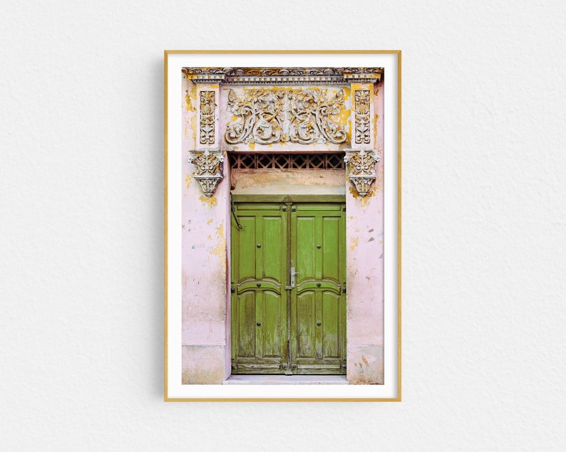 May include: A vintage green double door with ornate carvings above the door. The door is set in a pink building with faded paint.
