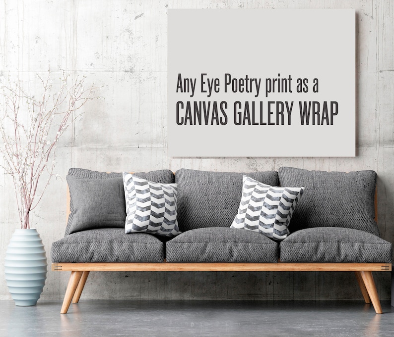 May include: A gray couch with two gray throw pillows and one black and white patterned throw pillow. The couch is in front of a gray wall with a white canvas print that says "Any Eye Poetry print as a CANVAS GALLERY WRAP".