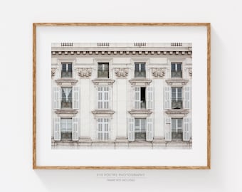 Puede incluir: Una impresión enmarcada que muestra una fachada detallada de un edificio con múltiples ventanas y contraventanas. El edificio está pintado en un color claro, con detalles arquitectónicos ornamentados. Las ventanas están abiertas y cerradas.
