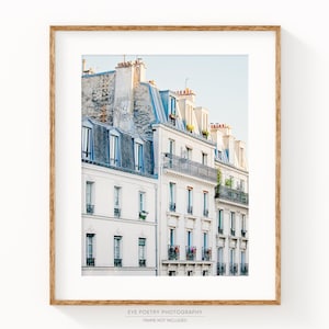 Puede incluir: Una fotograf&iacute;a de una fila de edificios blancos con techos azules en Par&iacute;s, Francia. Los edificios tienen balcones y ventanas. El cielo es de un azul claro.