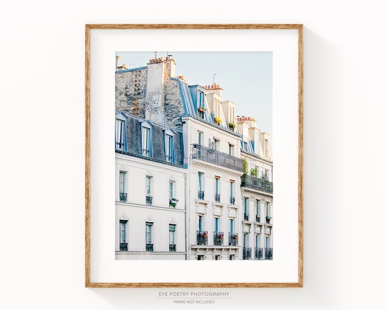 Puede incluir: Una fotograf&iacute;a de una fila de edificios blancos con techos azules en Par&iacute;s, Francia. Los edificios tienen balcones y ventanas. El cielo es de un azul claro.