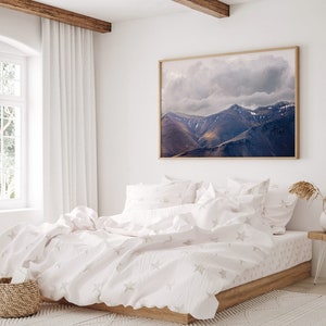 Puede incluir: Una cama blanca con una funda n&oacute;rdica blanca y fundas de almohada blancas. La funda n&oacute;rdica tiene un sutil patr&oacute;n de estrellas. La cama est&aacute; en un dormitorio con una ventana grande y una fotograf&iacute;a enmarcada de una cordillera.