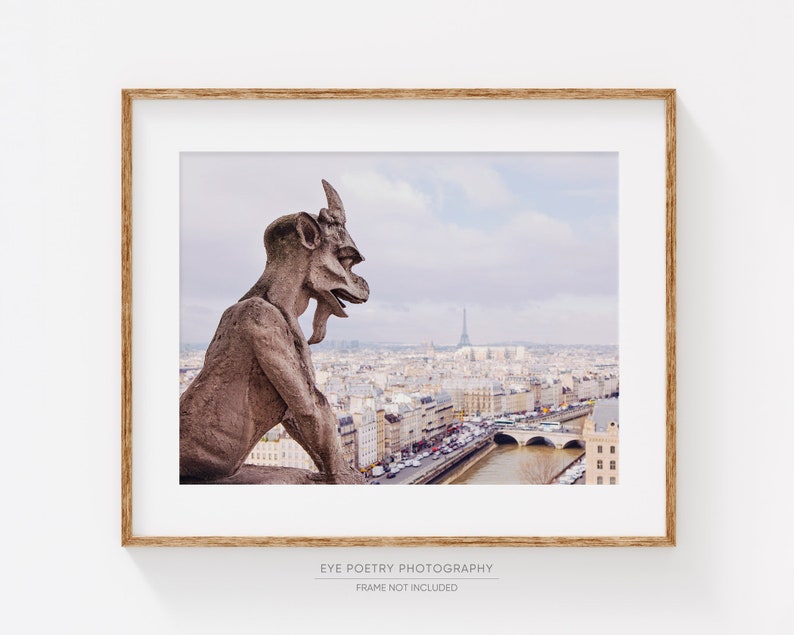 May include: A stone gargoyle sits atop a building overlooking the city of Paris, France. The Eiffel Tower is visible in the distance. The city is covered in a light dusting of snow.