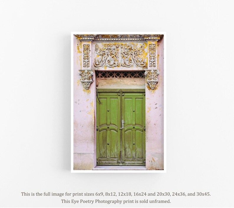 May include: A vintage green double door with ornate carvings above the door. The door is set in a pink building with faded paint.
