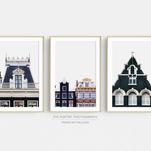 May include: Three framed prints of colorful buildings in Amsterdam, Netherlands. The prints feature a close-up of a building with a black roof and white trim, a row of buildings with black and red brick facades, and a green building with white trim and arched windows.