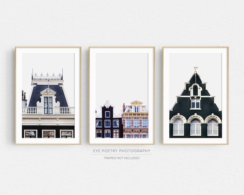 May include: Three framed prints of colorful buildings in Amsterdam, Netherlands. The prints feature a close-up of a building with a black roof and white trim, a row of buildings with black and red brick facades, and a green building with white trim and arched windows.