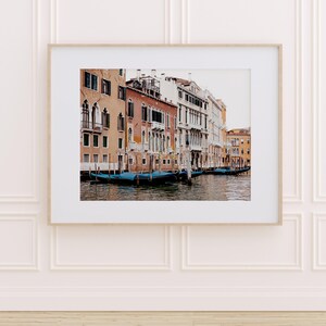 May include: A photograph of a canal in Venice, Italy. The canal is lined with colorful buildings and there are several gondolas in the water.