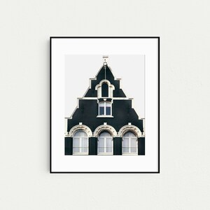 May include: A black and white photograph of a traditional Dutch house with a steep, gabled roof and arched windows. The house is painted a dark green color with white trim.