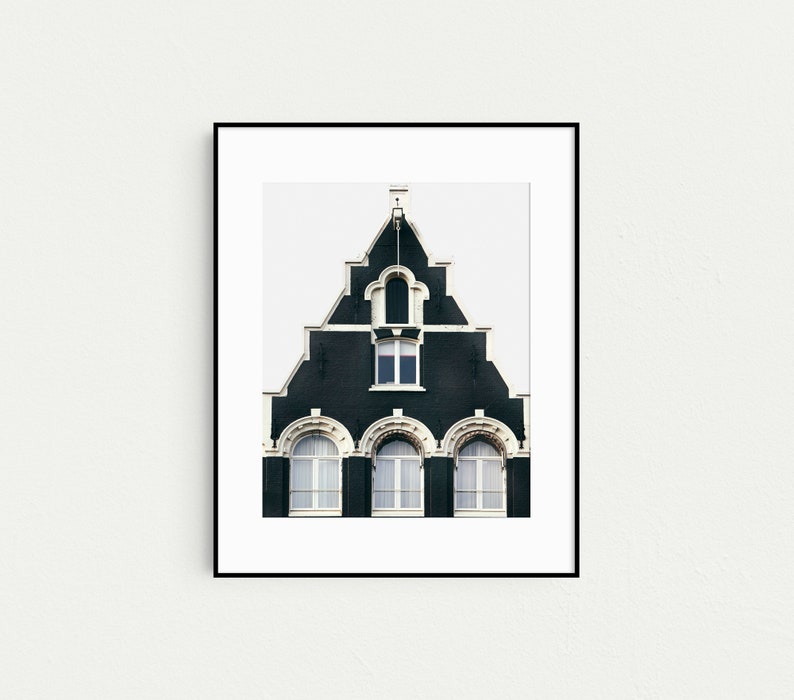 May include: A black and white photograph of a traditional Dutch house with a steep, gabled roof and arched windows. The house is painted a dark green color with white trim.