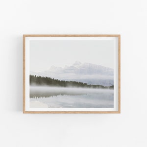 May include: A framed photograph of a mountain range reflected in a still lake with fog rolling in over a line of trees.