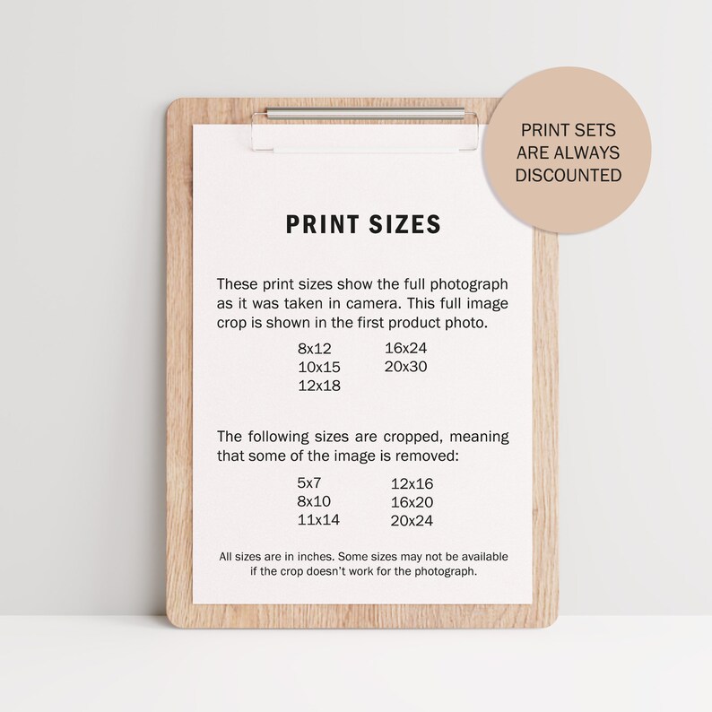 May include: A brown wooden clipboard with a white paper insert listing different print sizes in inches. The paper lists full image sizes and cropped sizes. The text "Print Sets Are Always Discounted" is written on a light brown circle in the top right corner.