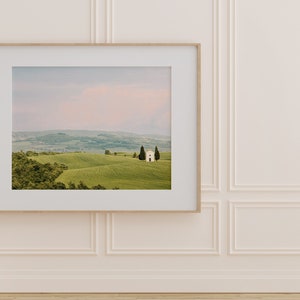May include: A framed photograph of a white building with a green roof, surrounded by rolling hills and trees. The sky is a soft pink and blue.
