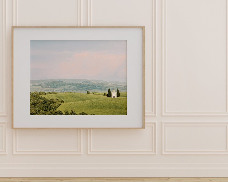 May include: A framed photograph of a white building with a green roof, surrounded by rolling hills and trees. The sky is a soft pink and blue.