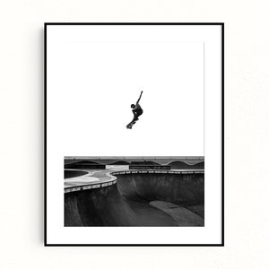 Peut inclure: Tirage encadr&eacute; en noir et blanc d'un skateur en plein saut au-dessus d'un skatepark. La silhouette du skateur se d&eacute;tache sur un ciel blanc, avec les courbes en b&eacute;ton du parc en contrebas. Une &oelig;uvre d'art contemporaine.